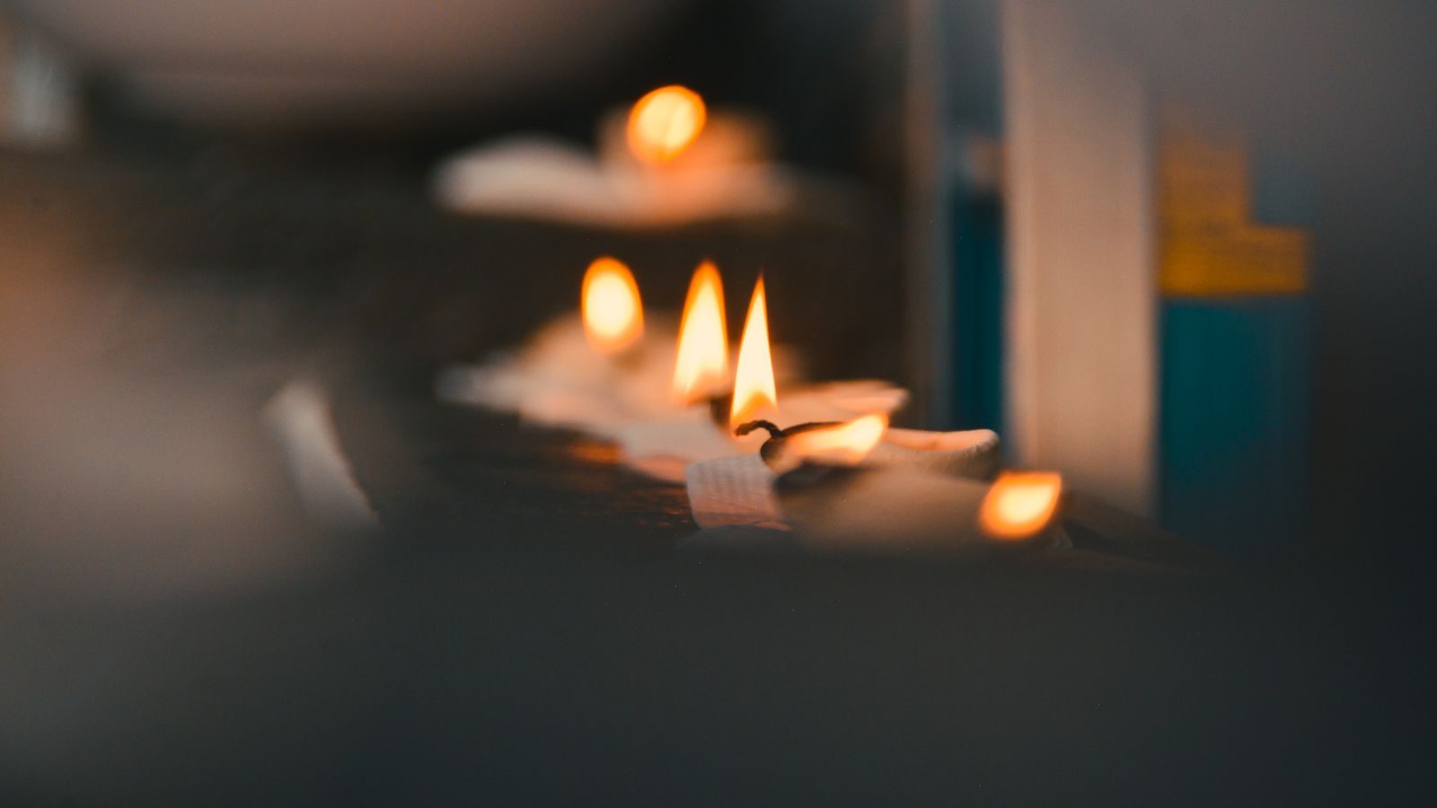 Three flickering candle flames in a row against a dark background.